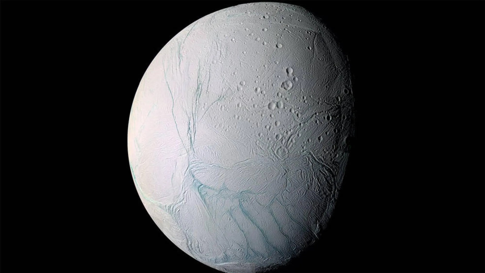 La corteza de hielo en el polo sur de Encélado muestra grandes fisuras que permiten que el agua del océano debajo de su superficie salga rociada al espacio en forma de géiseres, formando una columna de partículas congeladas.