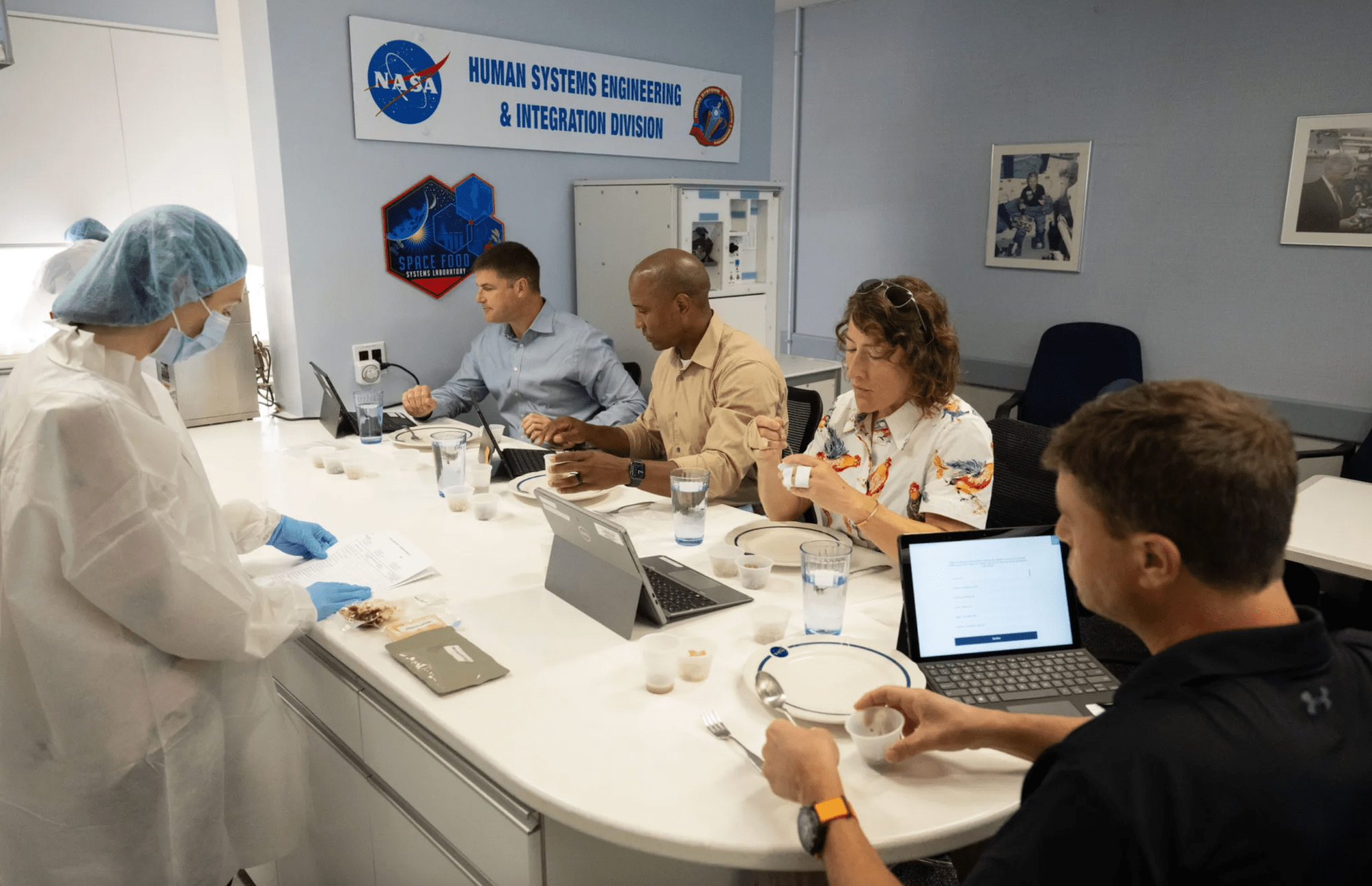 Los cuatro integrantes de la tripulación de Artemis II están sentados alrededor de una mesa en la que prueban alimentos, para seleccionar los que quieren llevar en su viaje alrededor de la Luna.
