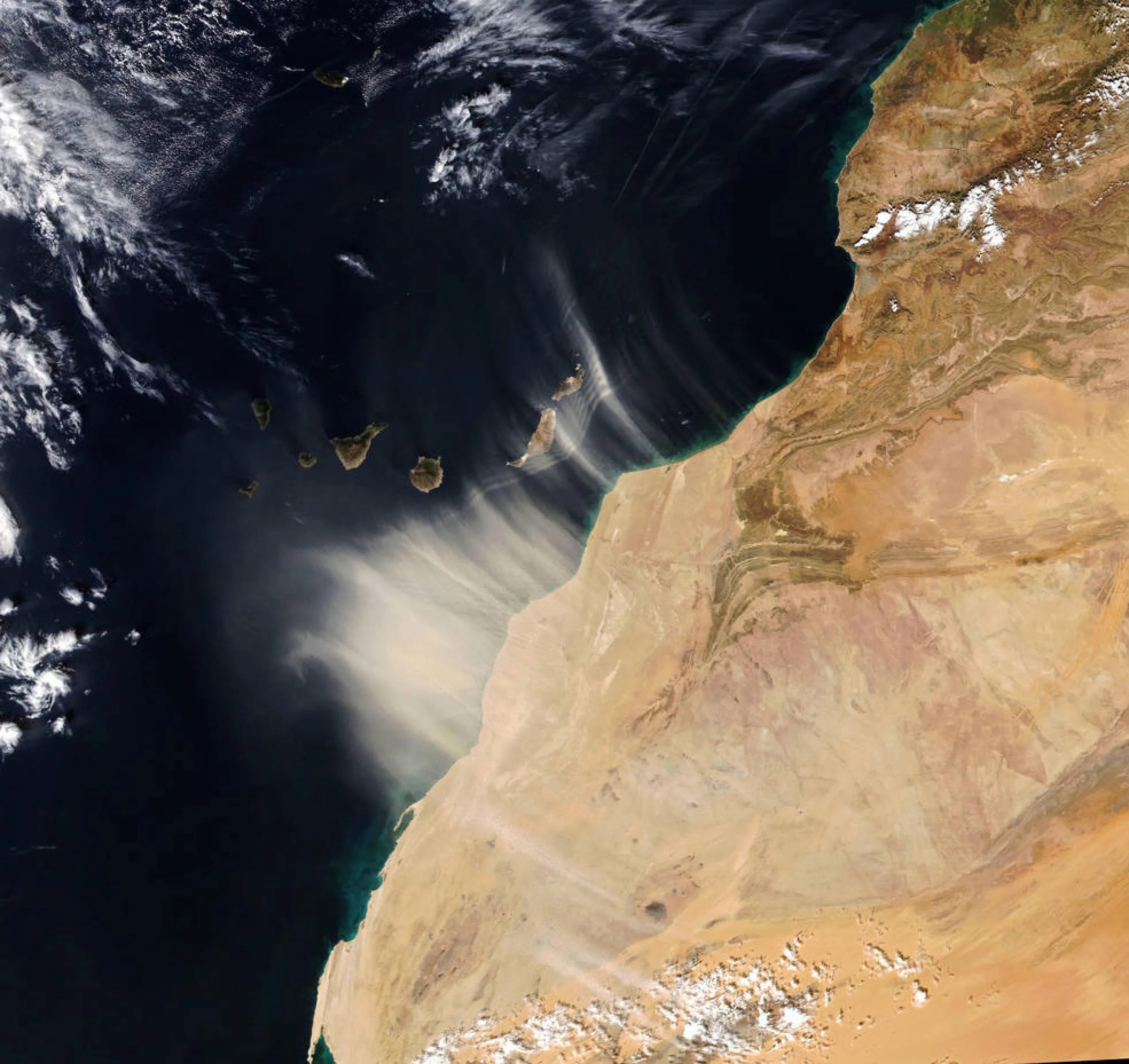 El viento con polvo proveniente del noroeste de África sopla sobre las islas Canarias en esta imagen capturada por el satélite NOAA 20 el 14 de enero de 2022. Una próxima misión de la NASA, la Investigación de las Fuentes de Polvo Mineral en la Superficie de la Tierra (EMIT, por sus siglas en inglés), ayudará a los científicos a comprender mejor qué papel desempeña el polvo en el aire en el calentamiento y enfriamiento de la atmósfera. Créditos: Observatorio de la Tierra de la NASA