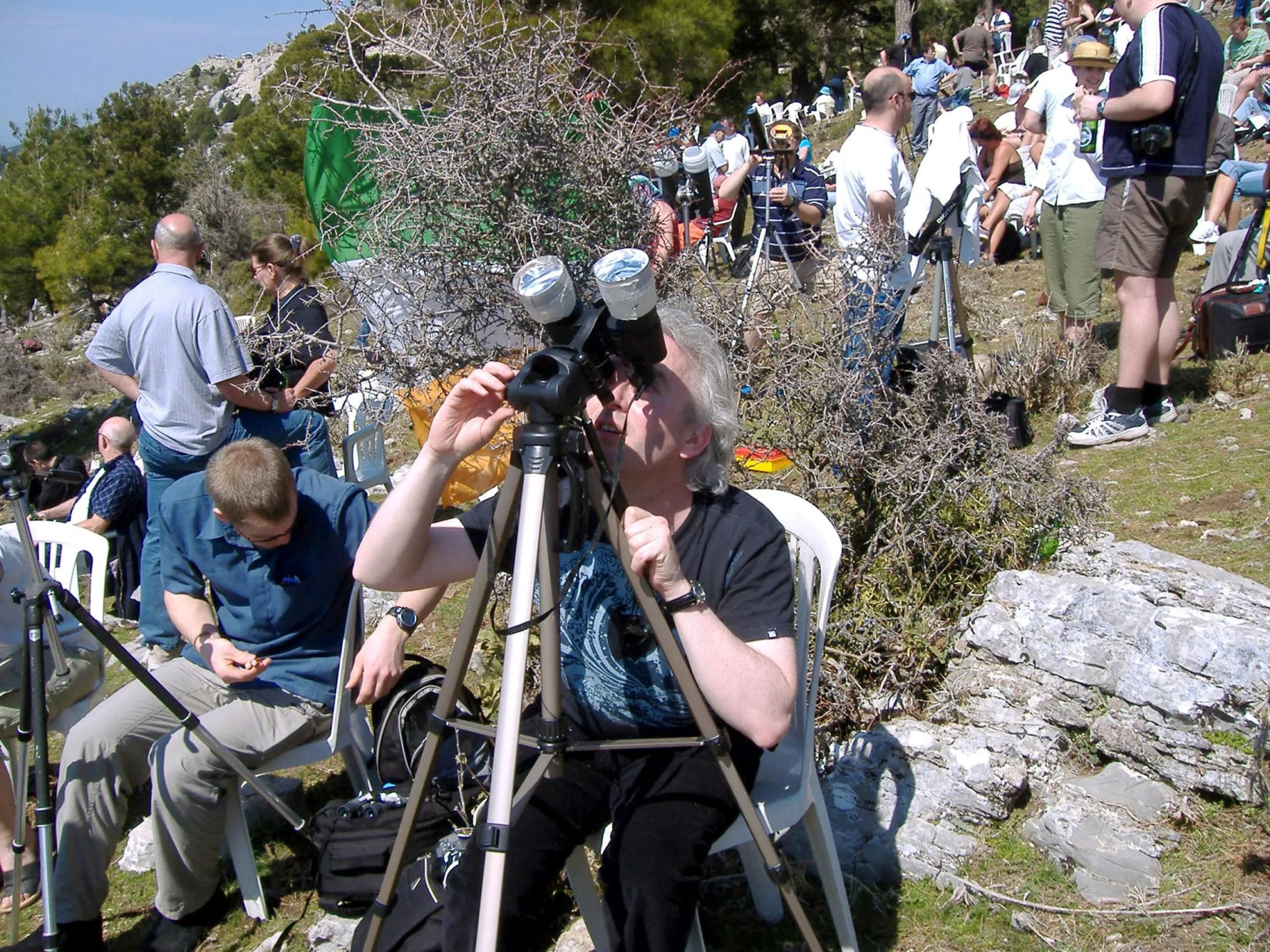 Imagen de una mujer observando el Sol a través de binoculares equipados con filtros solares.