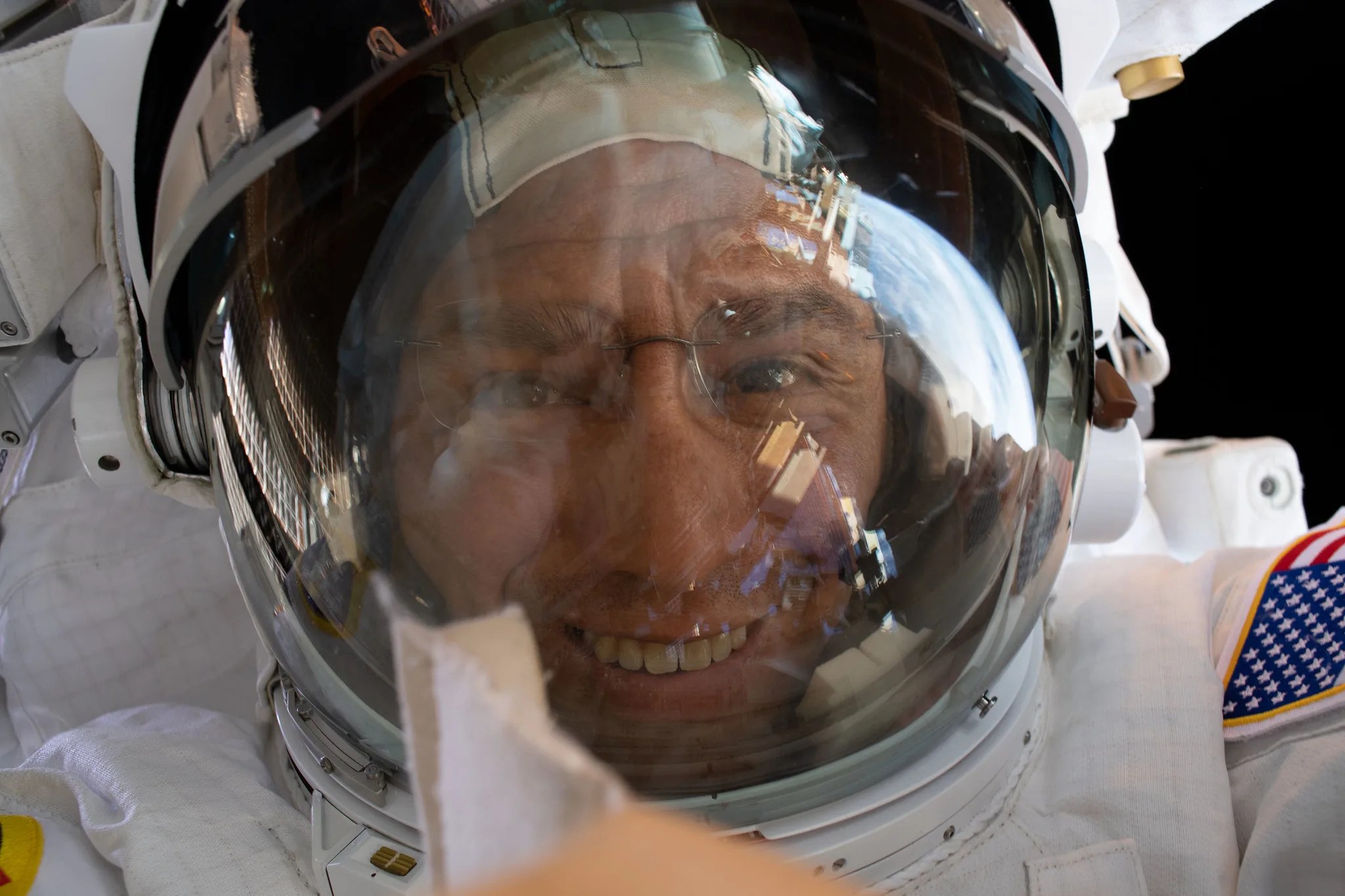 El astronauta de la NASA e ingeniero de vuelo de la Expedición 68, Frank Rubio, apunta su cámara hacia sí mismo y se hace un "selfie espacial" fuera de este mundo con la pantalla reflectante de su casco levantada durante una caminata espacial en su Unidad de Movilidad Extravehicular, o traje espacial.