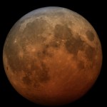 La Luna teñida de anaranjado contra el fondo negro.