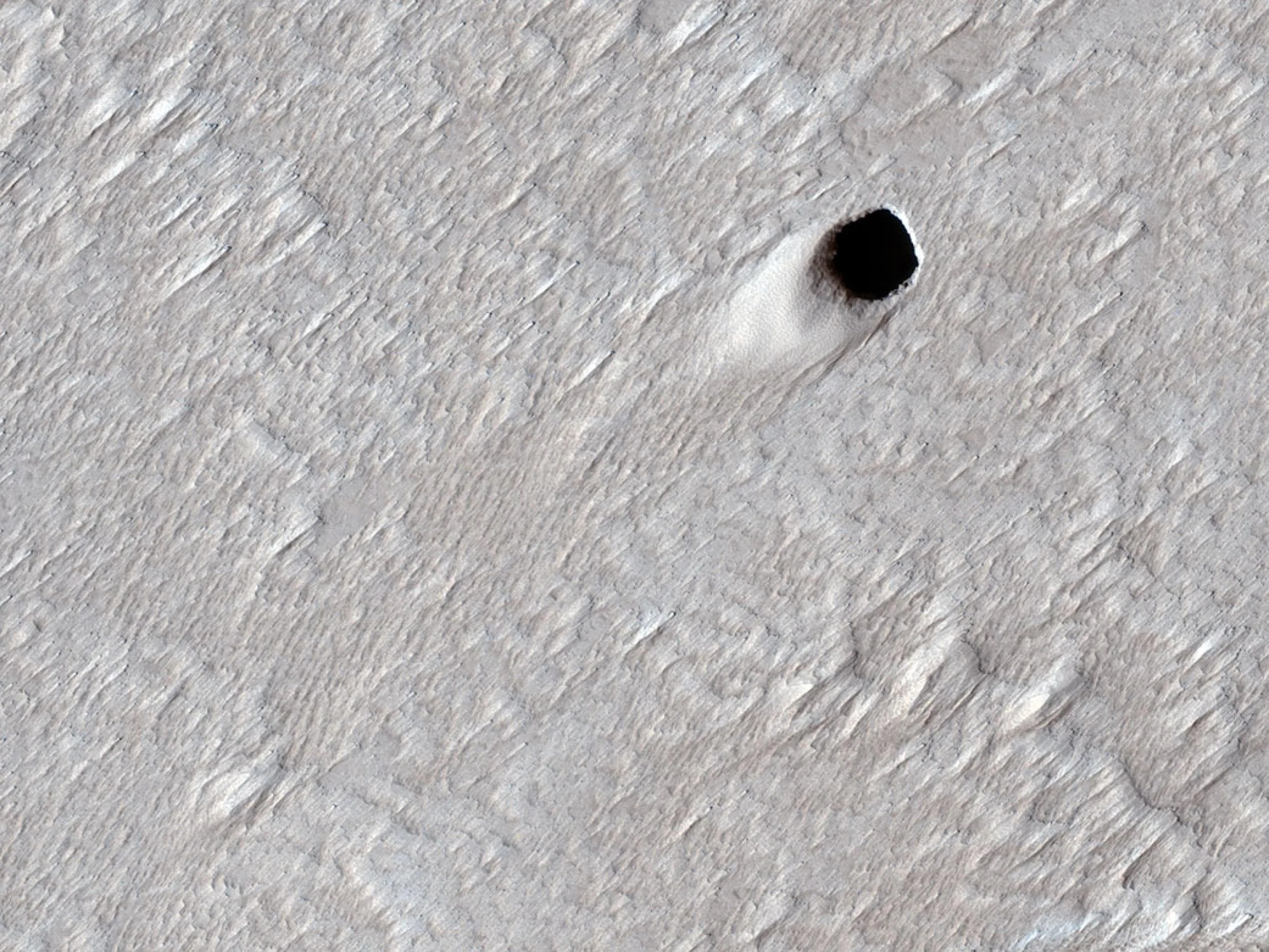 Este cráter de pozo fue creado por un tubo de lava vacío en la región de Arsia Mons de Marte. La imagen fue capturada por el Mars Reconnaissance Orbiter de la NASA el 16 de agosto de 2020. Créditos: NASA / JPL-Caltech / Universidad de Arizona