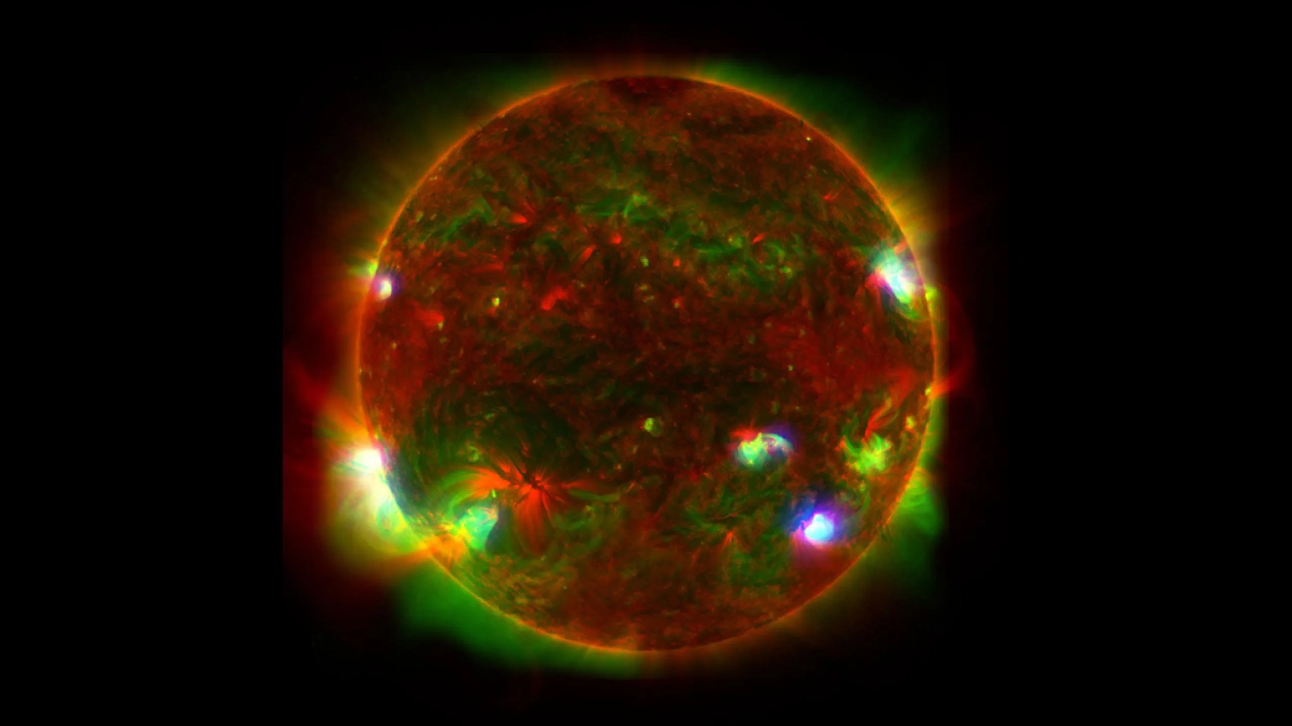 Imagen que muestra la luz de rayos X de alta energía del Sol detectada por el telescopio NuSTAR de la NASA. Predomina el rojo, el verde y el amarilloEl fondo es negro.