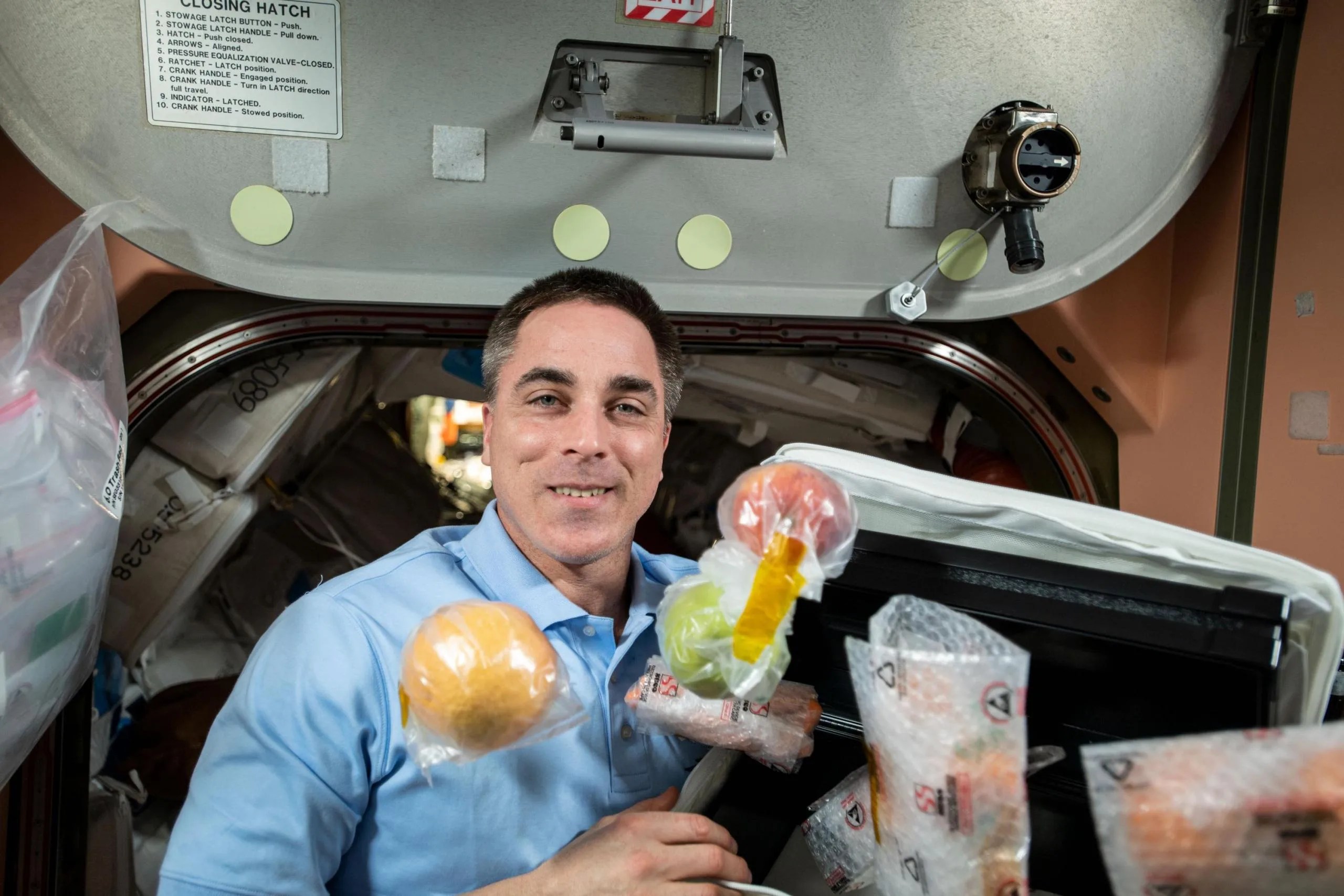 imagen de frutas frescas enteras y otros alimentos flotan alrededor del astronauta de la NASA Chris Cassidy