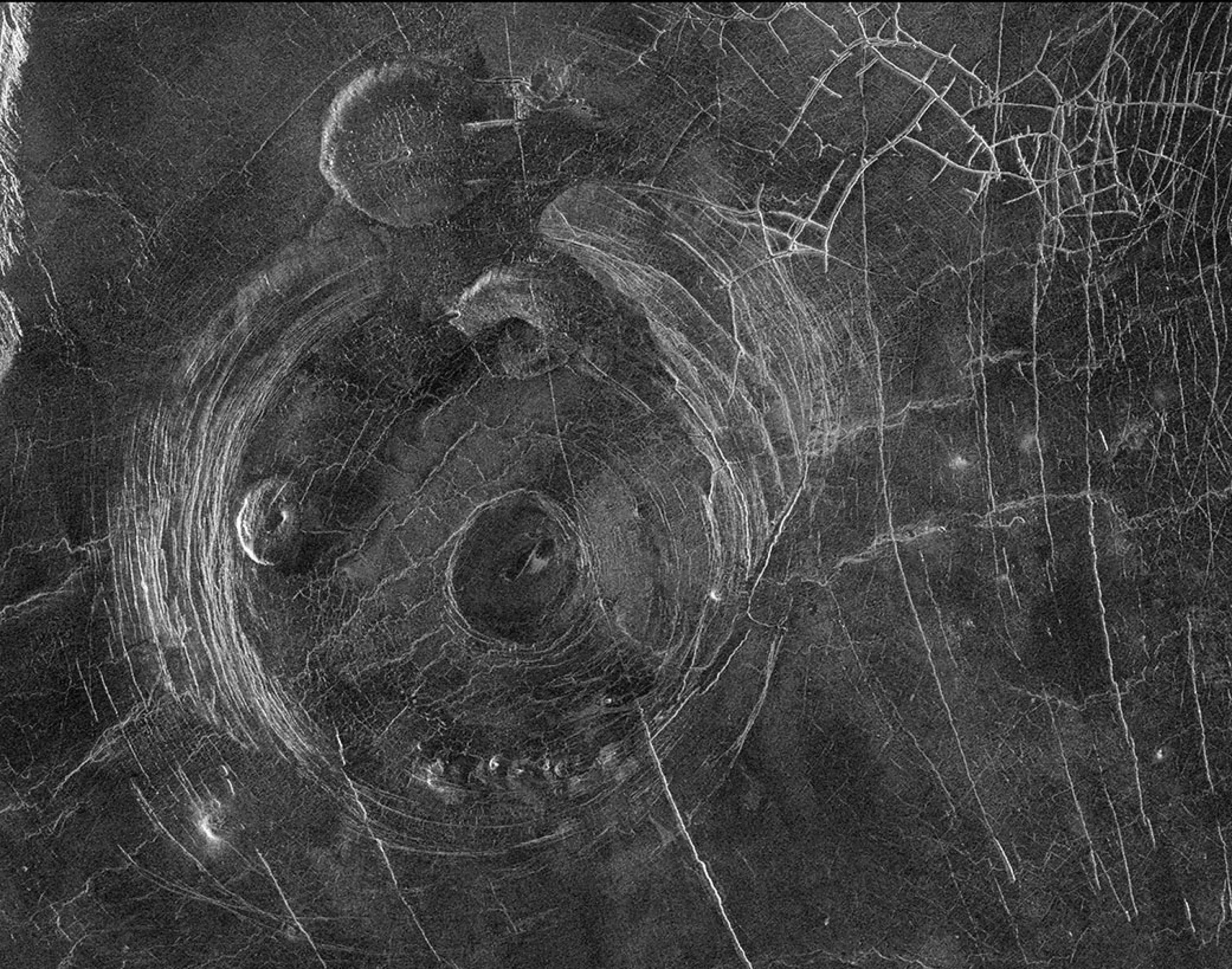 Esta imagen de radar de la misión Magallanes de la NASA muestra patrones circulares de fractura que rodean la corona Aine, ubicada en el hemisferio sur de Venus. La corona tiene alrededor de 200 kilómetros (124 millas) de ancho y muestra diversas características que podrían estar asociadas con actividad volcánica. Créditos: NASA/JPL-Caltech