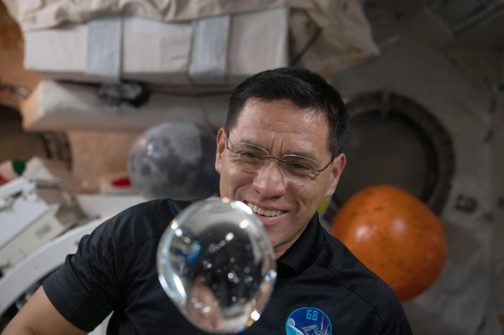 Astronauta Frank Rubio observando una de una burbuja de agua que flota libremente en la estación. Hispano/Latino de la NASA