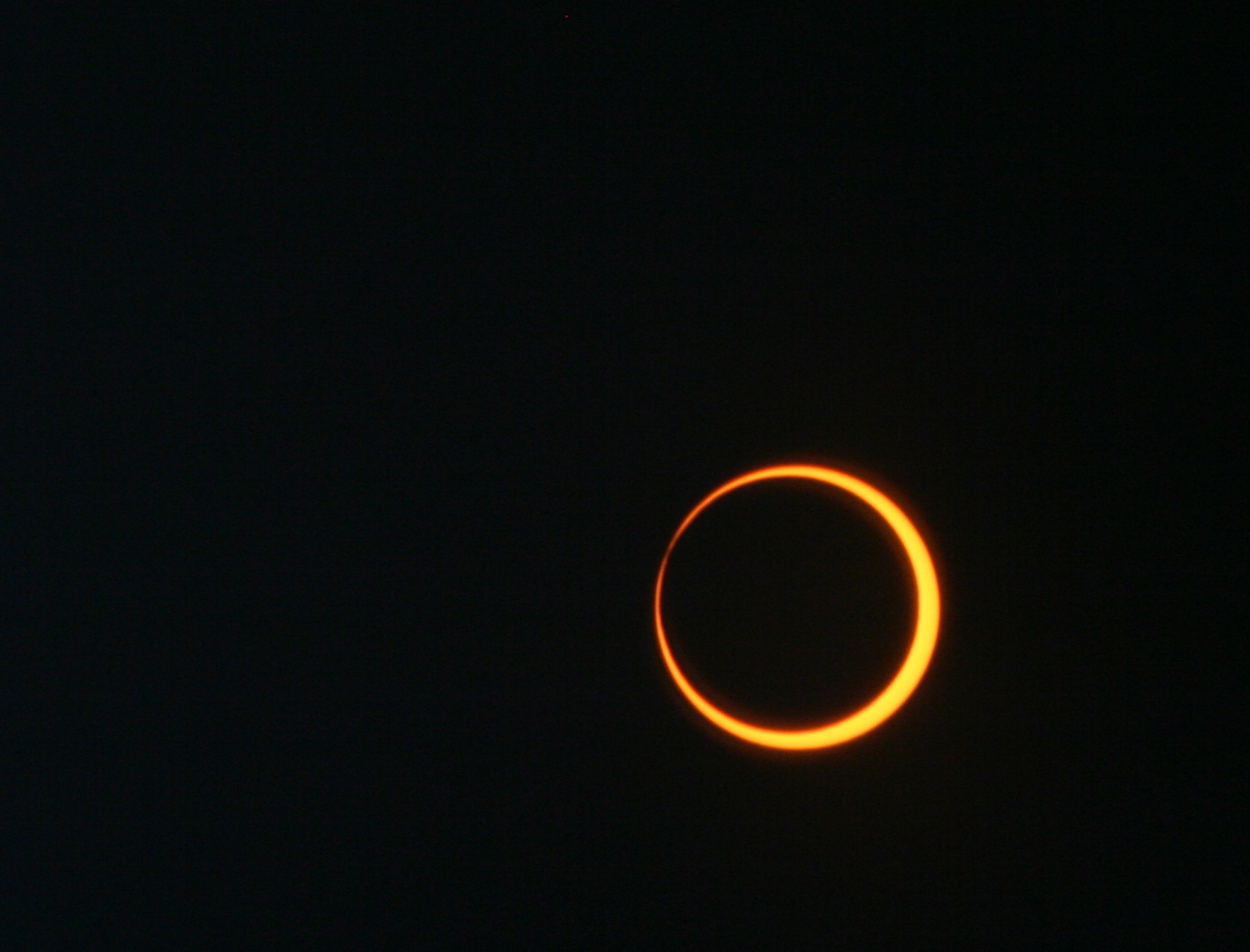 Un eclipse anular solar fotografiado el 20 de mayo de 2012. El Sol, un disco anaranjado brillante, en la esquina inferior derecha de la imagen, está siendo cubierto por un disco negro, la Luna.