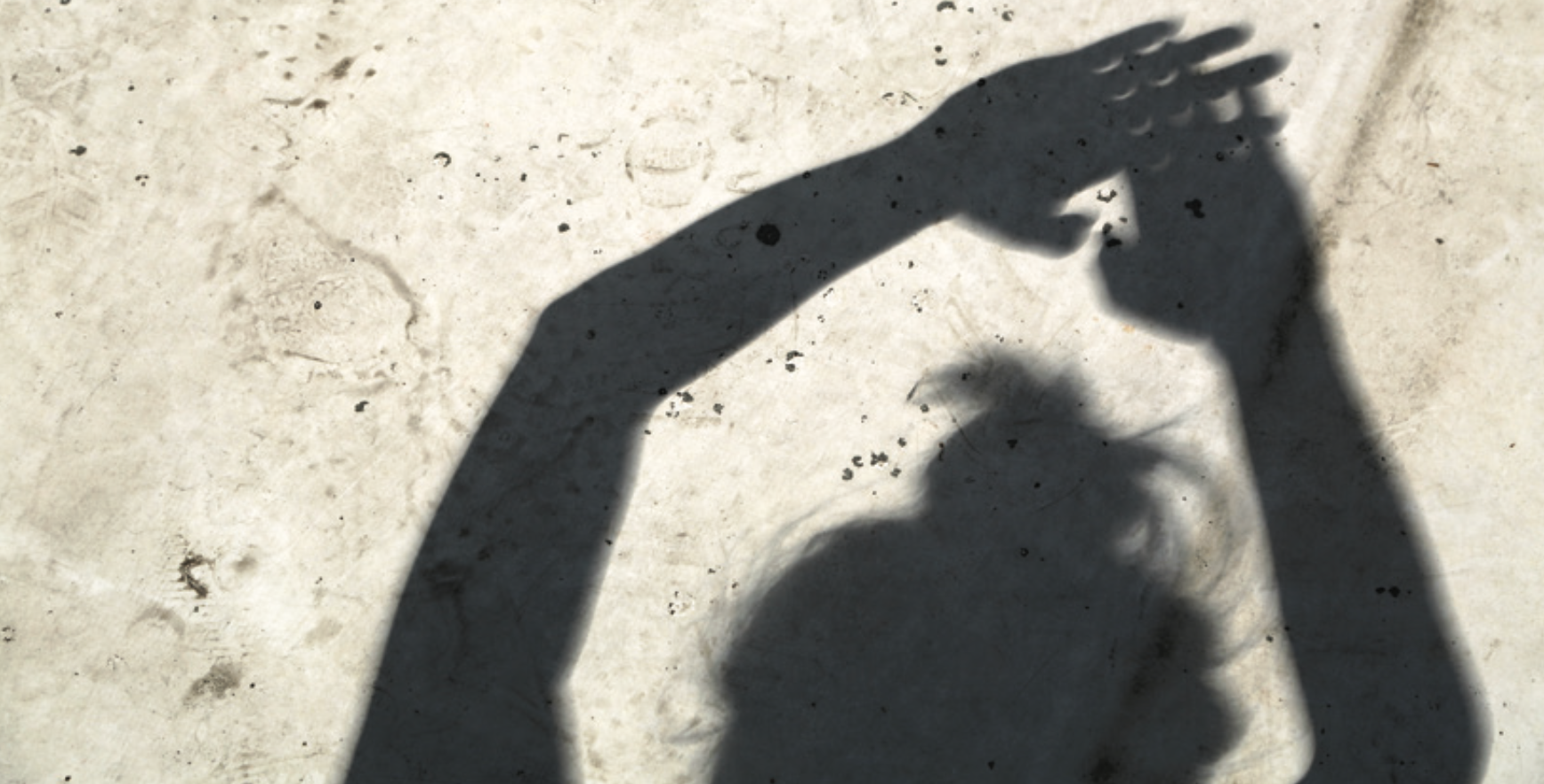 Foto que muestra la sombra de una persona con las manos extendidas hacia arriba. formando una "rejilla" con los dedos que hace posible ver un eclipse solar de forma indirecta.