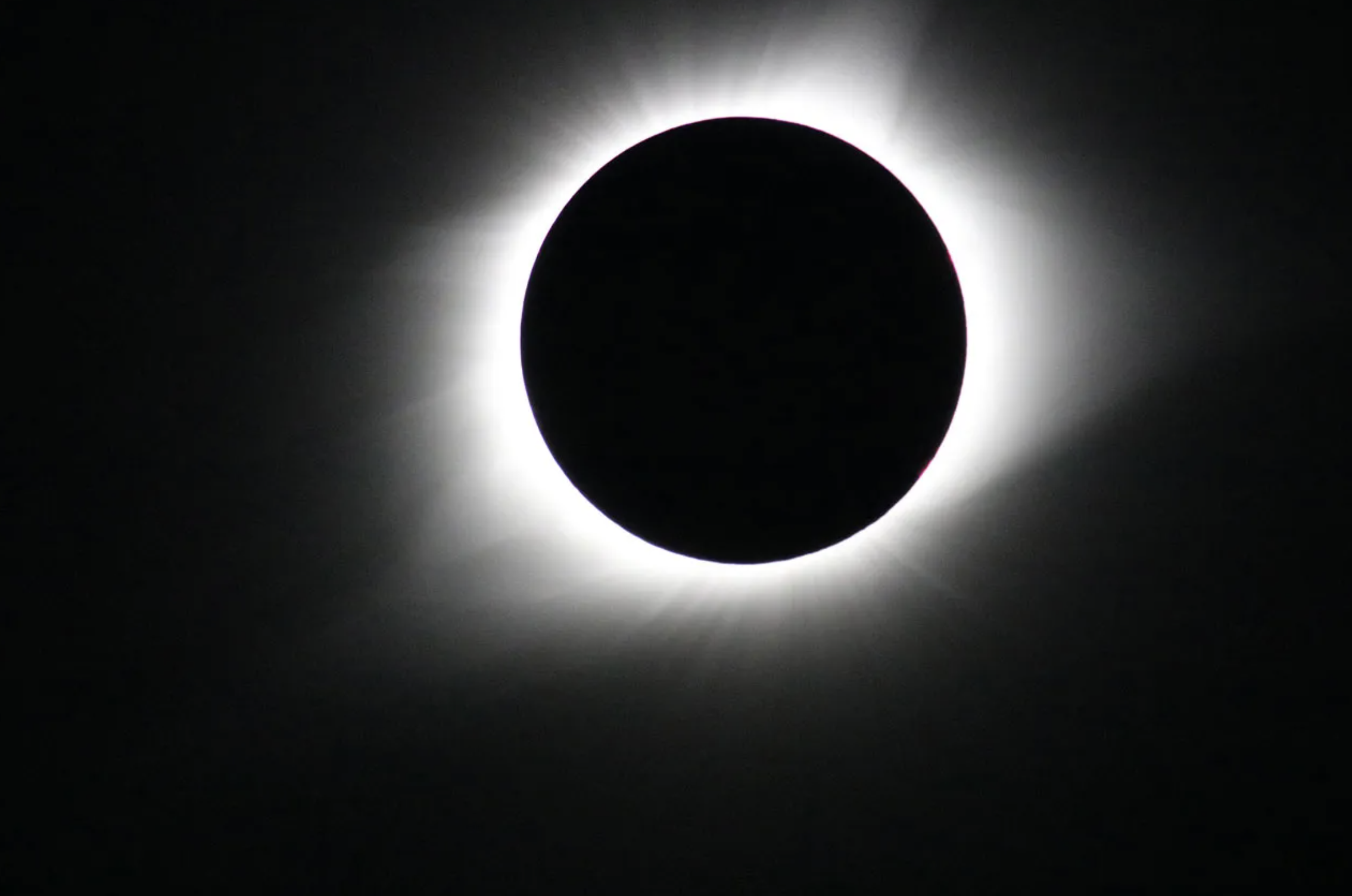 Esta imagen del eclipse solar total del 21 de agosto de 2017 fue tomada desde Madras, Oregón. El Sol aparece totalmente eclipsado por la Luna sobre un fondo negro. La corona del Sol, un halo blanco brillante, rodea el contorno de la Luna, un círculo negro en el centro de la imagen.